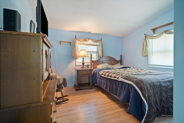 bedroom with light wood finished floors and vaulted ceiling