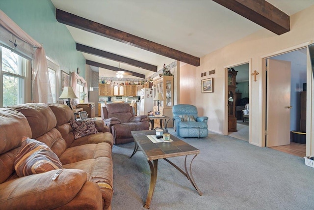 living room featuring lofted ceiling with beams, baseboards, and light colored carpet