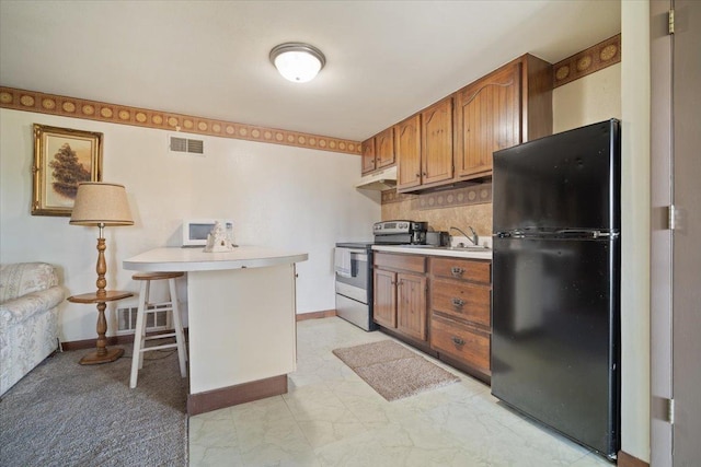 kitchen featuring visible vents, freestanding refrigerator, decorative backsplash, electric stove, and under cabinet range hood