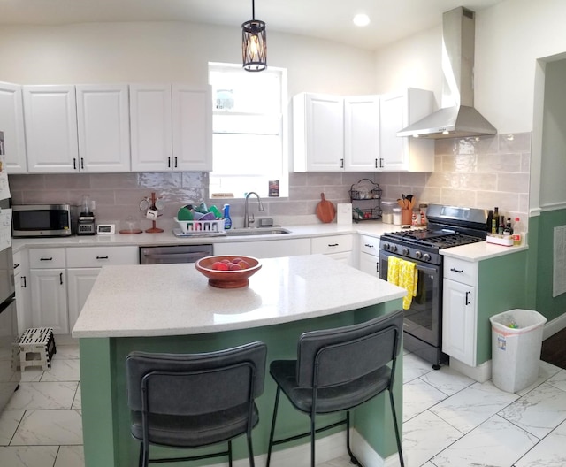 kitchen featuring marble finish floor, appliances with stainless steel finishes, wall chimney exhaust hood, and a sink