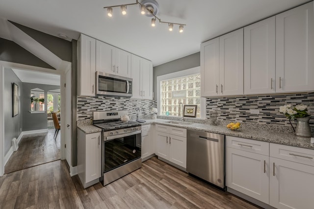 kitchen with sink, stainless steel appliances, light hardwood / wood-style flooring, decorative backsplash, and white cabinets