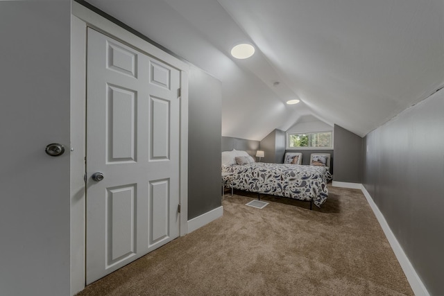 bedroom with light colored carpet and lofted ceiling