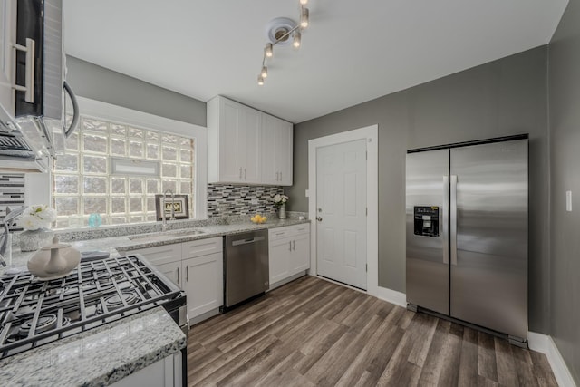 kitchen featuring white cabinetry, sink, light stone counters, backsplash, and appliances with stainless steel finishes