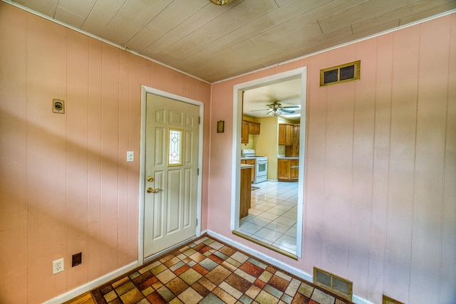 foyer entrance featuring ceiling fan, wood ceiling, and wooden walls