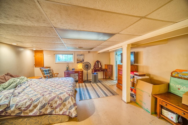 bedroom with a paneled ceiling and concrete flooring