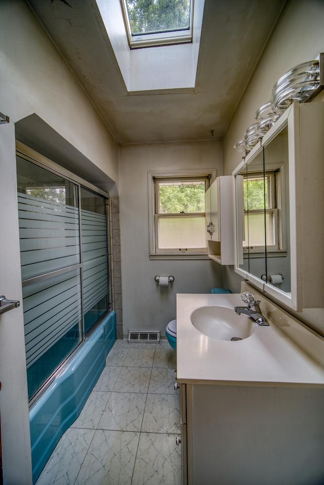 full bathroom featuring vanity, toilet, enclosed tub / shower combo, and a skylight