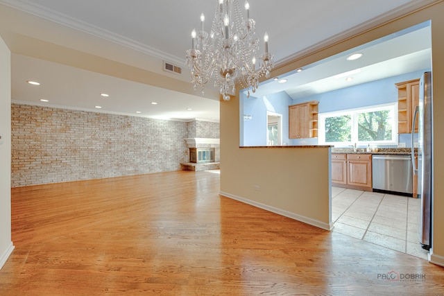 interior space featuring light hardwood / wood-style floors, crown molding, a chandelier, and brick wall