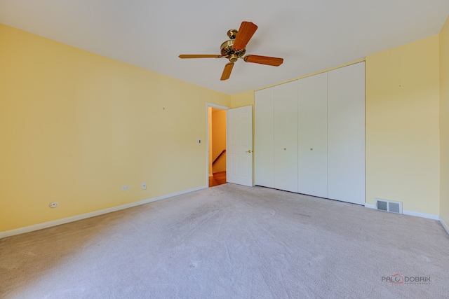 unfurnished bedroom with light colored carpet, a closet, and ceiling fan