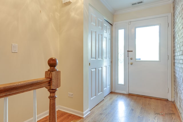 foyer entrance with brick wall, crown molding, and wood-type flooring