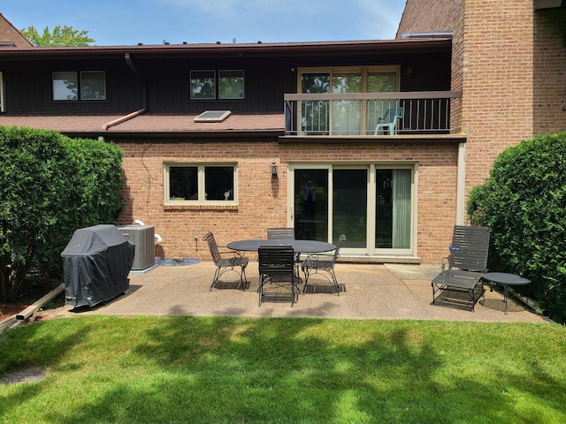 rear view of property featuring a yard, a patio area, central AC, and a balcony