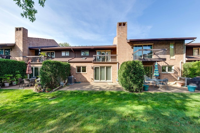 back of house with a balcony, central AC, a patio, and a lawn