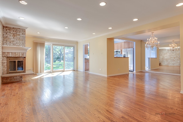 unfurnished living room with light hardwood / wood-style flooring, ornamental molding, and a brick fireplace