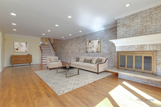 living room featuring light hardwood / wood-style floors, ornamental molding, brick wall, and a fireplace