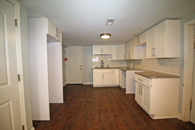 kitchen featuring dark hardwood / wood-style flooring, backsplash, sink, stone counters, and white cabinets