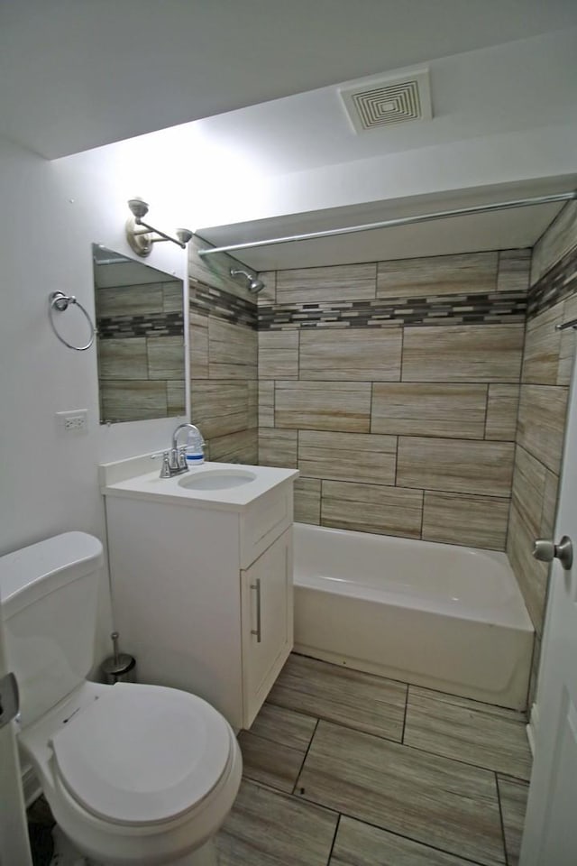 full bathroom featuring tiled shower / bath combo, toilet, and vanity