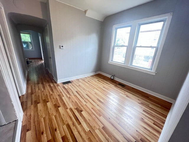 unfurnished room featuring wood-type flooring and wood walls