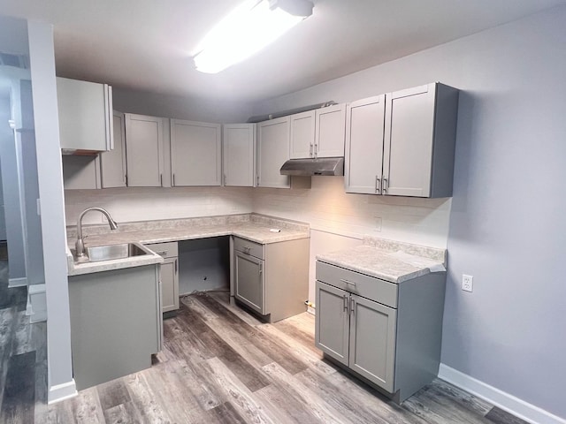 kitchen featuring gray cabinetry, sink, backsplash, and light hardwood / wood-style flooring