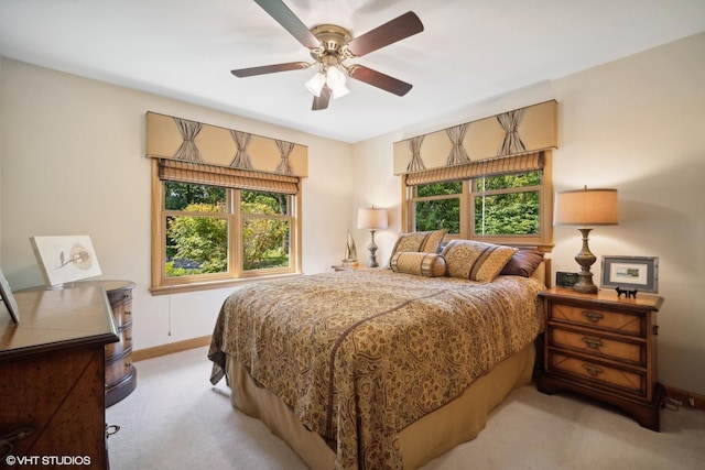 bedroom featuring multiple windows, baseboards, and light carpet