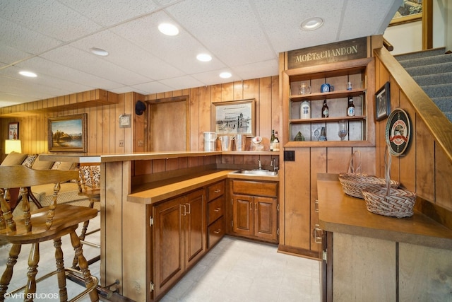 bar with recessed lighting, a sink, a bar, stairs, and wood walls