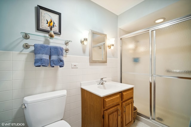 bathroom with an enclosed shower, toilet, vanity, tile walls, and tile patterned floors