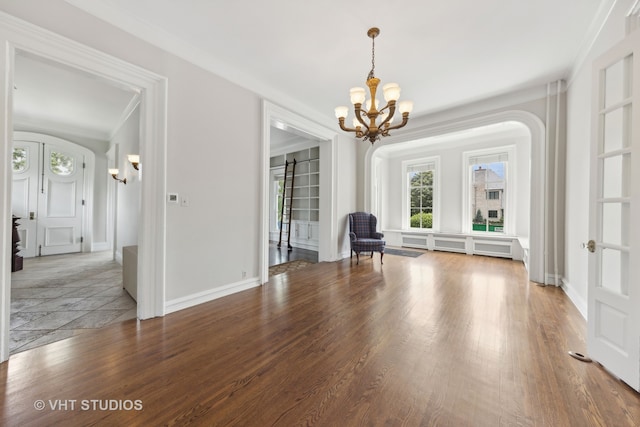 unfurnished room featuring crown molding, hardwood / wood-style floors, and an inviting chandelier