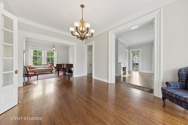 living area with crown molding, dark wood-type flooring, and a chandelier