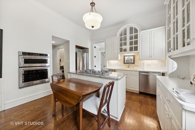 kitchen featuring appliances with stainless steel finishes, dark wood-type flooring, decorative light fixtures, white cabinets, and a center island