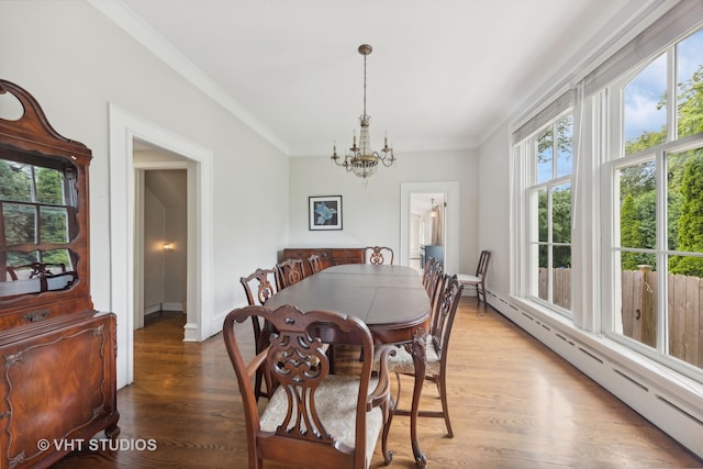 dining area featuring hardwood / wood-style flooring, crown molding, a baseboard radiator, and an inviting chandelier