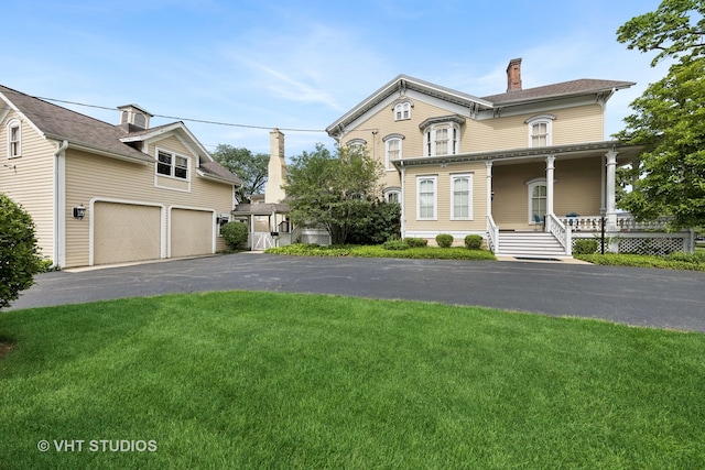 front of property with covered porch, a garage, and a front lawn