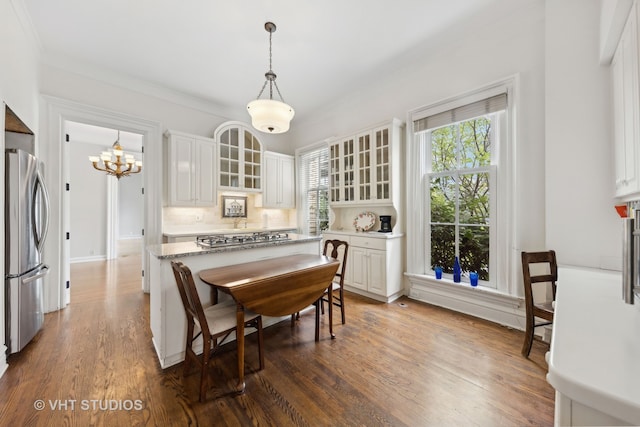 kitchen featuring dark hardwood / wood-style flooring, tasteful backsplash, stainless steel appliances, white cabinets, and hanging light fixtures