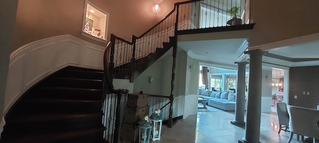 staircase featuring tile flooring, ornamental molding, and ornate columns