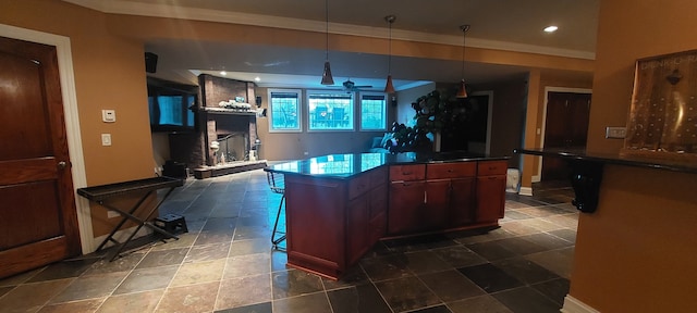 kitchen with dark tile flooring, a large fireplace, a breakfast bar area, and pendant lighting