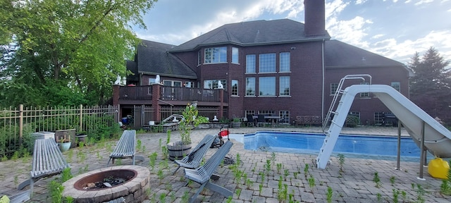 back of house with an outdoor fire pit, a pool side deck, and a patio