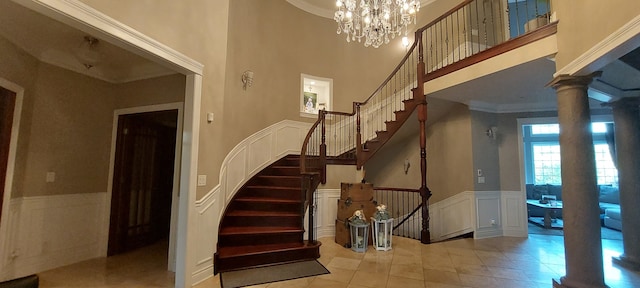 staircase featuring a notable chandelier, a towering ceiling, decorative columns, and light tile floors