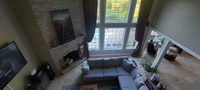 living room with a healthy amount of sunlight, a stone fireplace, and a high ceiling