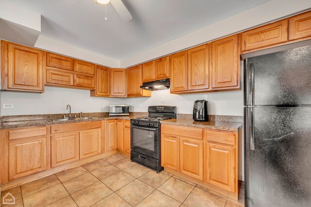 kitchen featuring stone counters, black appliances, sink, ceiling fan, and light tile patterned floors