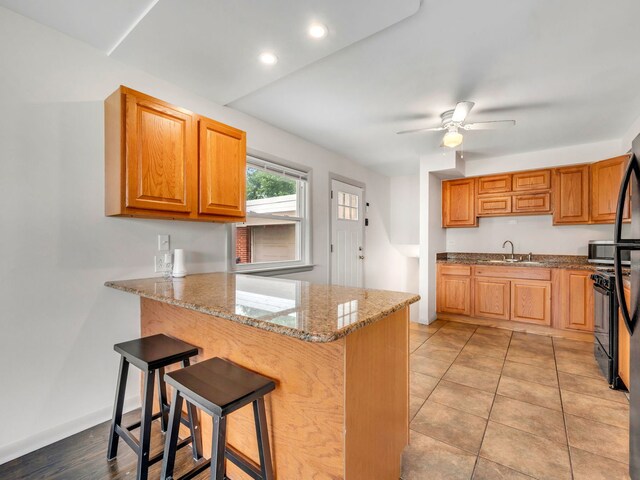 kitchen with ceiling fan, kitchen peninsula, and light tile patterned floors