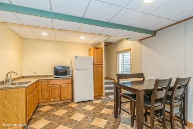 kitchen featuring white refrigerator, sink, and a drop ceiling