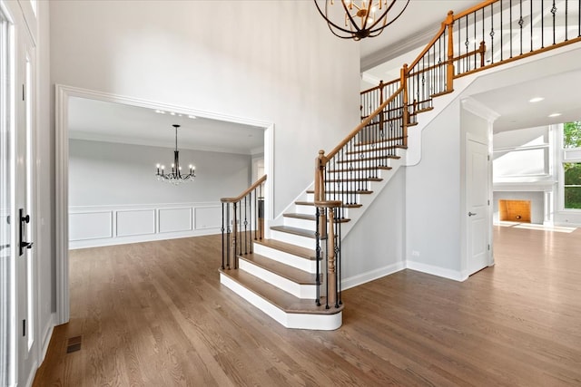 stairs featuring hardwood / wood-style flooring, crown molding, and an inviting chandelier