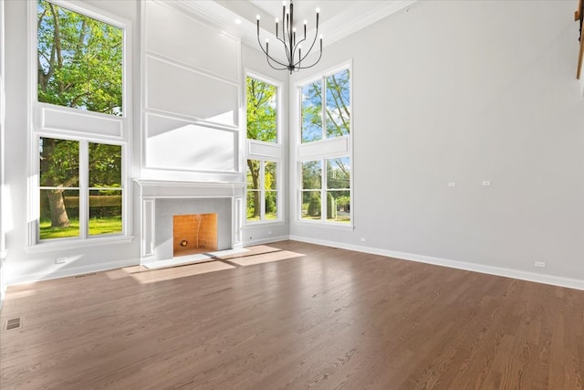 unfurnished living room featuring dark hardwood / wood-style flooring, ornamental molding, a high ceiling, and a notable chandelier