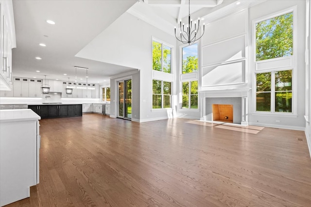 unfurnished living room with dark hardwood / wood-style flooring, a towering ceiling, and a chandelier