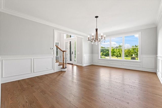 unfurnished dining area with crown molding, a notable chandelier, and hardwood / wood-style flooring