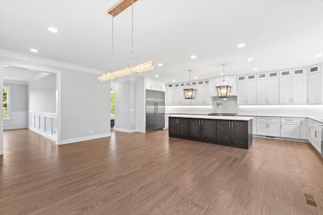 kitchen with white cabinetry, stainless steel built in refrigerator, decorative light fixtures, a kitchen island, and ornamental molding