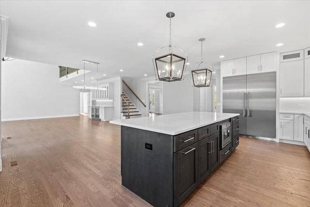 kitchen with pendant lighting, a center island, white cabinets, stainless steel built in fridge, and light hardwood / wood-style floors