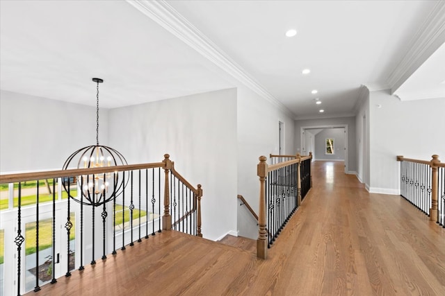 hallway with light hardwood / wood-style floors, crown molding, and an inviting chandelier