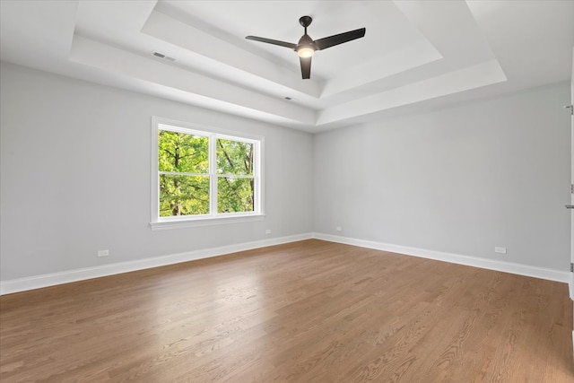 empty room featuring hardwood / wood-style floors, a tray ceiling, and ceiling fan