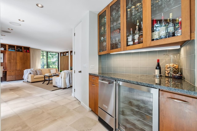 bar with wine cooler, fridge, decorative backsplash, and dark stone countertops