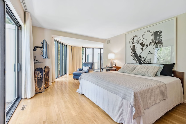 bedroom with light hardwood / wood-style floors and expansive windows
