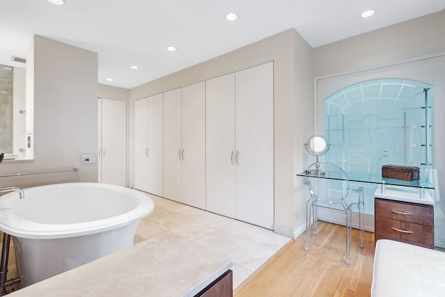 bathroom featuring vanity, wood-type flooring, and a bathing tub