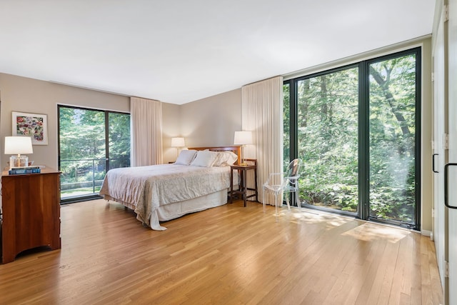 bedroom with floor to ceiling windows, access to outside, and light hardwood / wood-style flooring